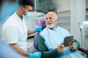 older man in dental chair discussing with dental professional about the benefits of cosmetic dentistry