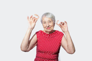 excited older woman showing off her dentures after receiving tips for first-time denture wearers