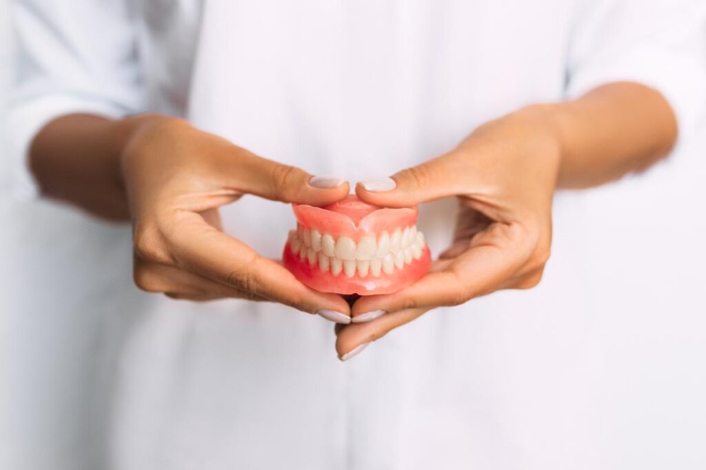 dental professional holding a set of dentures as she explains the denture myths debunked by denture facts