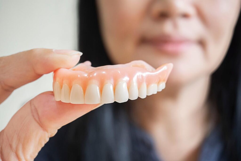 image of dental professional holding up a set of dentures as she explains the complete guide to dentures