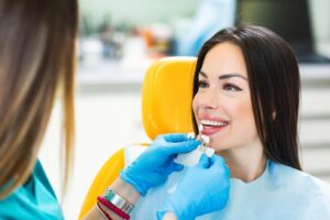 dental specialist explaining to woman the difference between veneers vs. crowns and which is the best opiton for your smile