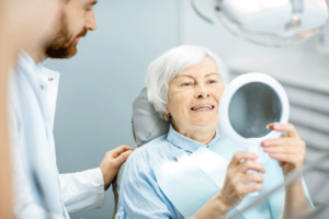 older woman reclining in dental chair as she talks with her prosthodontist and asks, "Do I need TMD treatment?"