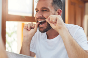 young man flossing at home and demonstrating tips for preventing cavities