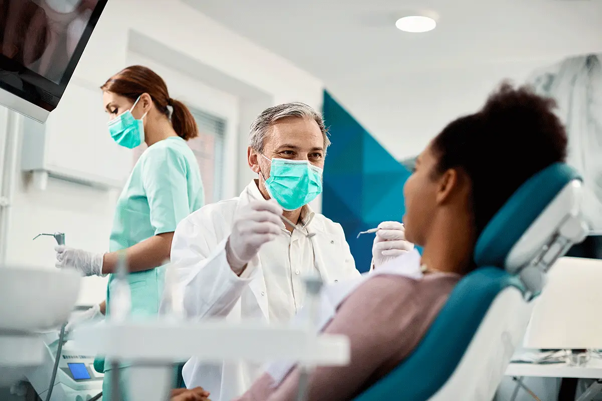 A man and woman wearing dental masks converse while conducting an oral cancer screening